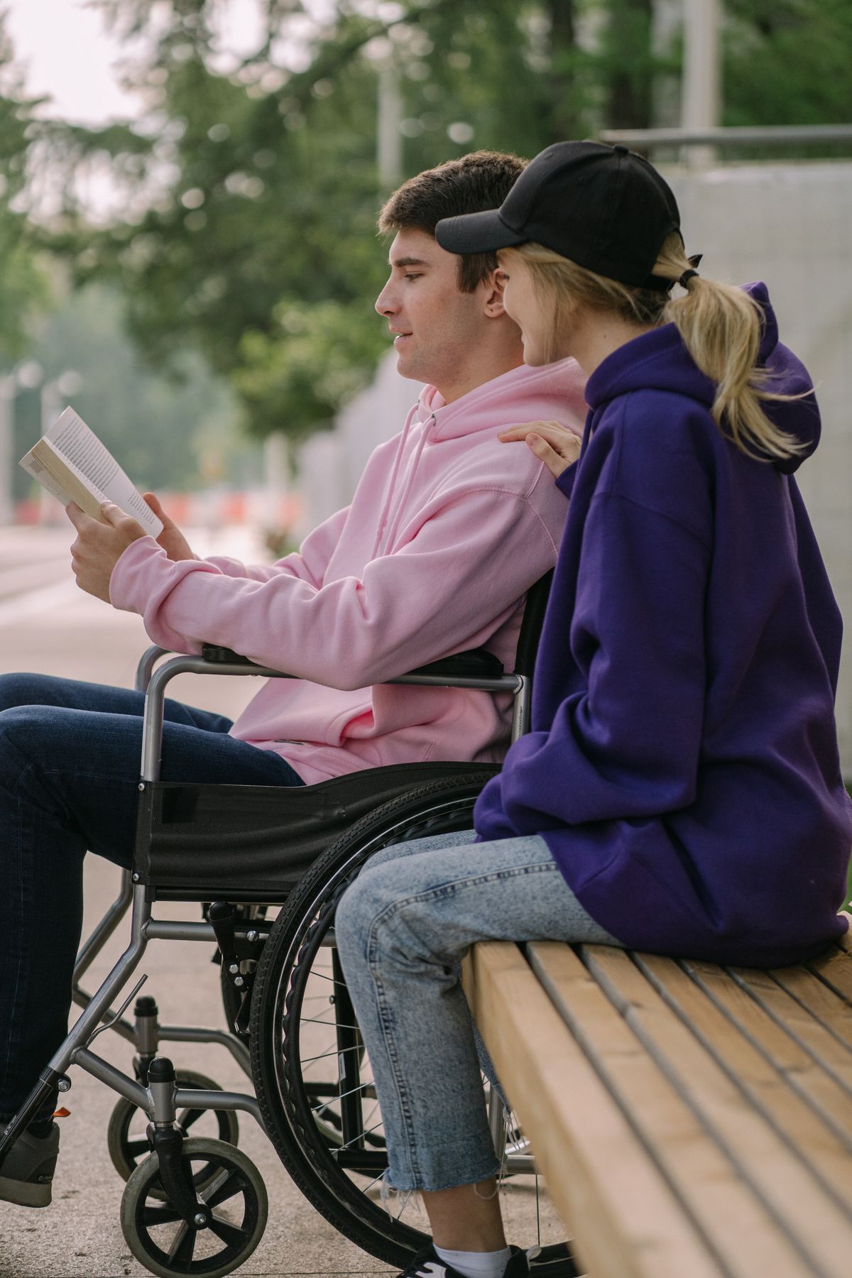 A wheelchair user and a friend reading together outdoors